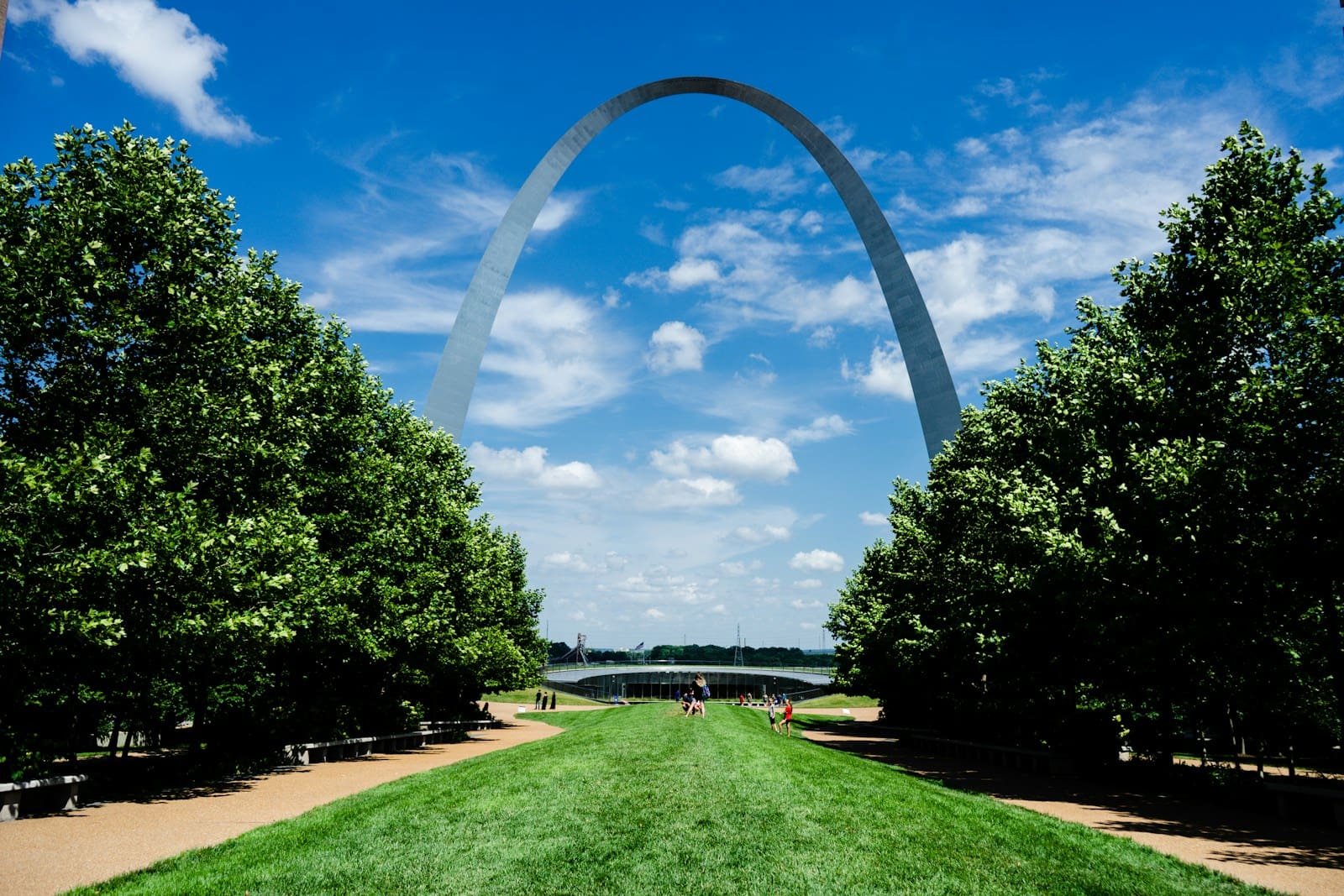 green grass field with trees under blue sky and white clouds during daytime